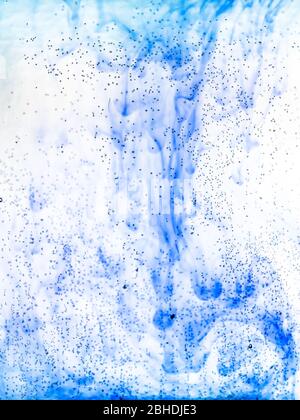 bolle d'aria sulla superficie di vetro della bottiglia piatta e acquerelli blu fluiscono in acqua sullo sfondo Foto Stock