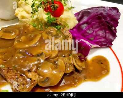 Foto di bistecca di maiale bianca con sugo e cavolo sul piatto bianco Foto Stock