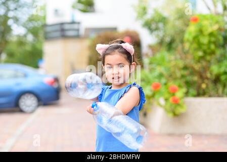 Bambina che guarda la macchina fotografica e che tiene bottiglie d'acqua di plastica per il riciclaggio. Giornata mondiale dell'ambiente. Foto Stock