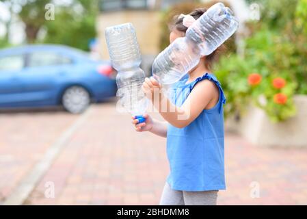 Bambina che tiene bottiglie d'acqua di plastica per il riciclaggio. Concetto di plastica mondo libero, il futuro per i nostri bambini. Zero sprechi. Foto Stock