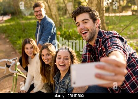 Gruppo di studenti nel Parco divertendosi insieme makign un selfie Foto Stock