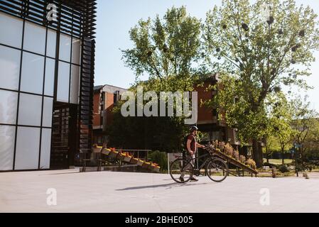 Bel giovane caucasico che porta la bicicletta sulla scala Foto Stock