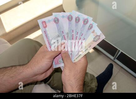 Valuta nazionale degli Emirati Arabi Uniti. Banconote in UAE. Il giovane uomo tiene in mano sporca denaro di carta. Foto Stock