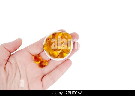La mano femmina contiene capsule di olio di pesce isolate su bianco. Foto Stock