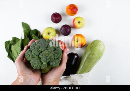 Mani femminili che tengono broccoli. Zero rifiuti, cure, concetto di salute. Vista superiore, spazio copia, disposizione piatta. Foto Stock
