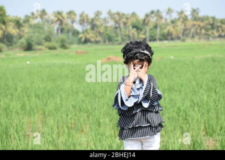 Ragazza piccola che si sente felice mentre gioca fuori.campo di papà in background. Foto Stock