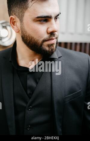 giovane uomo elegante e serio con barba che indossa abiti formali Foto Stock