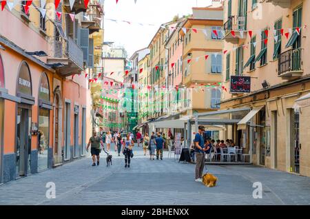 La Spezia, Italia, 13 settembre 2018: Persone con cani che camminano lungo la strada pedonale principale con bandiere sopra nel centro storico della città in estate, Liguria Foto Stock