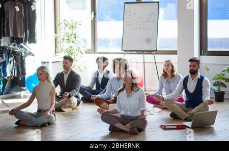 gruppo di colleghi di lavoro che meditano al lavoro, seduti sul pavimento. concetto moderno, aziendale, meditazione Foto Stock