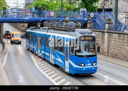 Tram a Cracovia mentre la gente attraversa la strada attraverso il ponte pedonale Foto Stock