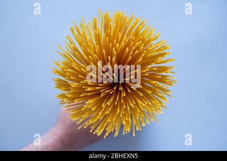 Prendi fila, spaghetti crudi accatastati insieme. Pasta o maccheroni italiani. Uccello occhio, vista dall'alto, sfondo blu tavolo. Prodotti di pasta secca. Foto Stock