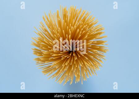 Fila, spaghetti non cotti accatastati insieme. Pasta o maccheroni italiani. Uccello occhio, vista dall'alto, sfondo blu tavolo. Prodotti di pasta secca. Foto Stock