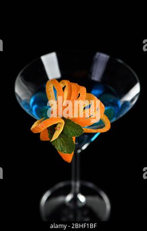 Decorazione per un cocktail di arancia e menta. Presentazione elegante e originale. Martini Blue Curacao su sfondo nero Foto Stock