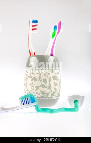 Dentifricio verde e spazzolini multicolore in un bicchiere speciale accanto a un tubo di dentifricio. Ancora vita. Foto Stock