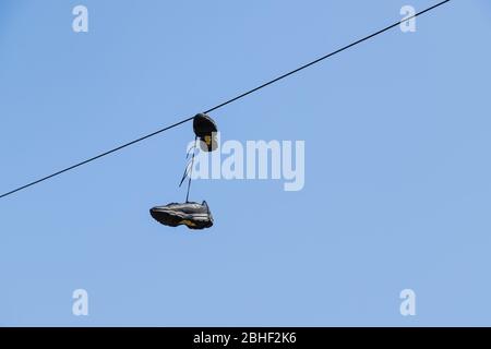 Guardando in alto le scarpe nere appese da un filo telefonico vicino a Liverpool. Foto Stock