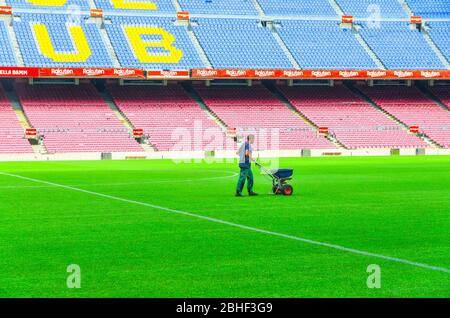 Barcellona, Spagna, 14 marzo 2019: Il lavoratore semina erba con spargipula di fertilizzanti sul prato del campo verde Camp Nou, tribune si trova sullo sfondo. Stadio della squadra di calcio Barcellona Foto Stock