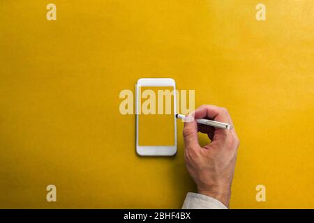Un primo piano sopra l'angolo della mano di una persona che tiene una penna stylus su uno smartphone bianco vuoto pronto per qualsiasi cosa da scrivere nell'immagine da busi Foto Stock