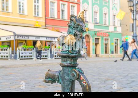 Wroclaw, Polonia, 7 maggio 2019: Il nano è seduto sul rubinetto d'acqua della strada sulla piazza del mercato Rynek, famoso gnome in miniatura di bronzo con la scultura del cappello è un simbolo di Wroclaw nel centro storico della città vecchia Foto Stock