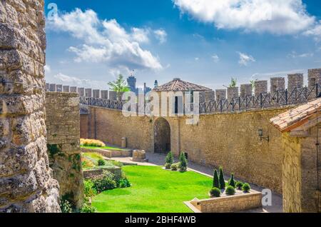 Repubblica San Marino, 18 settembre 2018: Mura fortilizio in mattoni di pietra con merli e cortile della prima Torre Guaita prima torre e seconda Torre la testa sulla roccia del Monte Titano con cielo blu Foto Stock