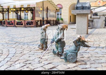 Wroclaw, Polonia, 7 maggio 2019: Tre nani: Sordi, ciechi con un bastone e invalidi in una sedia a rotelle, famoso gnomo in bronzo in miniatura con la scultura del cappello è un simbolo di Wroclaw nel centro storico della città vecchia Foto Stock