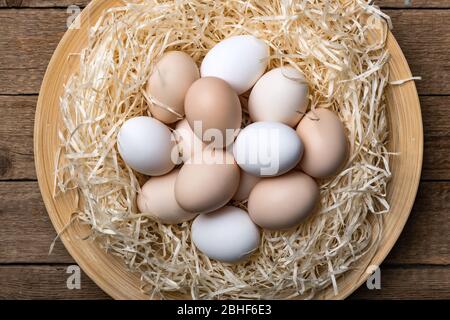 Uova di pollo biologiche in nido su sfondo di legno. Fotografia alimentare Foto Stock