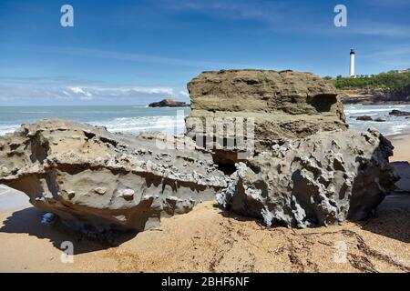 Pietre su una spiaggia e faro. Situato a Biarritz, Francia Foto Stock