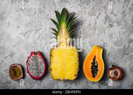 Ananas, Papaya, Maracuya frutto della passione, Pitaya frutto del drago e Mangosteen su sfondo grigio cemento. Concetto di frutta tropicale esotica. Fotografia alimentare Foto Stock