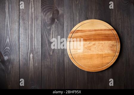 Tagliere rotondo su tavolo di legno marrone. Vista dall'alto Foto Stock