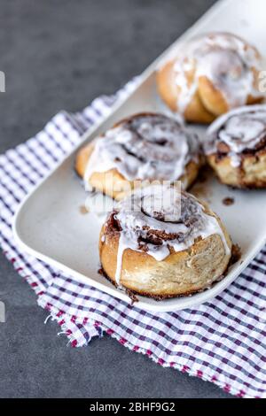 Panini alla cannella fatti in casa preparati su un piatto con tovagliolo per la colazione Foto Stock