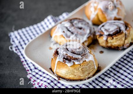 Panini alla cannella fatti in casa preparati su un piatto con tovagliolo per la colazione Foto Stock