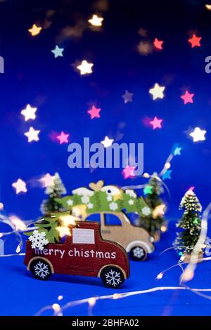 Piccola auto giocattolo rossa in legno su sfondo blu con lucido sfondo bokeh. Natale e Capodanno festa di festa Concept.festive decorazione e. Foto Stock