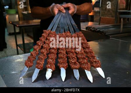 Spiedini di carne su spiedini di acciaio in fila Foto Stock