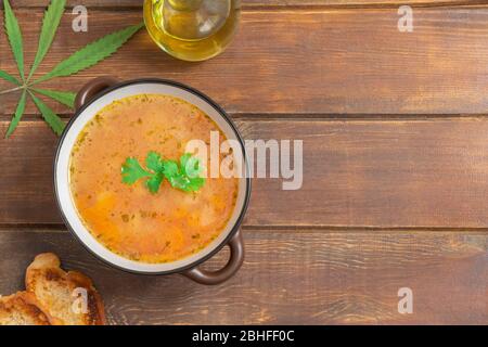 Vista dall'alto della zuppa di cannabis vegetale in una ciotola su sfondo di legno con spazio per le copie Foto Stock