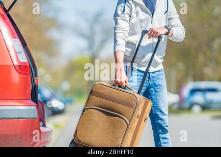 valigia in mano, il giovane uomo tirato dal bagagliaio del passeggero automobile Foto Stock