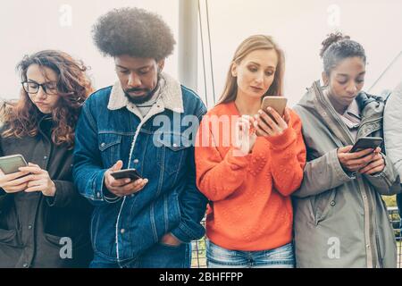 Persone che scelgono i loro telefoni oltre l'interazione personale Foto Stock