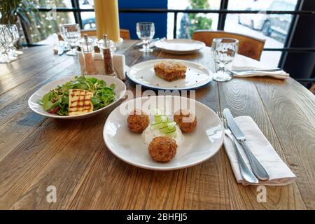 Set di tre piatti greci - formaggio saganaki fritto, moussaka e zucchine frittelle sul tavolo del ristorante Foto Stock