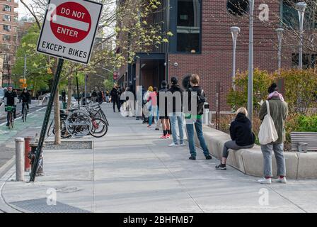 I newyorkesi aspettano in fila per entrare nel Target a New York City durante la pandemia COVID-19. Foto Stock