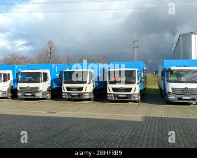 Berlino, Germania - 18 gennaio 2020: In una fila più Mercedes-Benz Atego camion accanto a Man camion in parcheggio di fronte a magazzino edificio con dramma Foto Stock