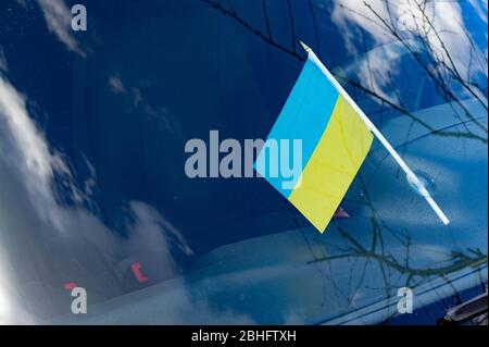 Bandiere nazionali ucraine attaccate al cristallo del parabrezza automatico sotto i tergicristalli dell'auto Foto Stock