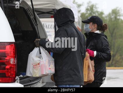 Frontenac, Stati Uniti. 25 Aprile 2020. I volontari della St. Louis Area Foodbank rimuovono le donazioni di cibo dal retro di un'auto sotto la pioggia, a Frontenac, Missouri, sabato 25 aprile 2020. La pandemia di coronavirus ha svuotato le dispense dell'alimento nella zona. Foto di Bill Greenblatt/UPI Credit: UPI/Alamy Live News Foto Stock