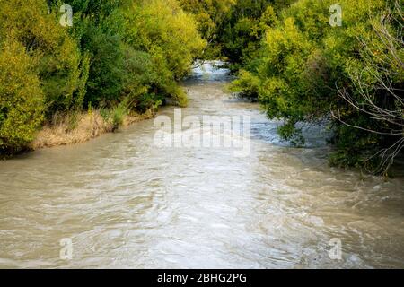 L'acqua sporca scorre rapidamente lungo il fiume dopo giorni di forti piogge Foto Stock