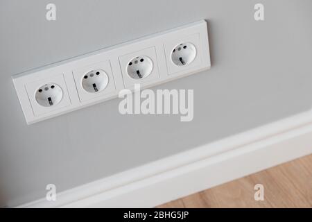 Prese europee bianche su pareti in cemento grigio in stile loft, con zoccolo in poliuretano alto Foto Stock