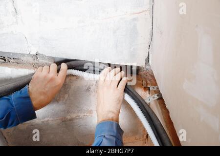 Installation of pipe channel for connecting air conditioner in concrete wall Foto Stock