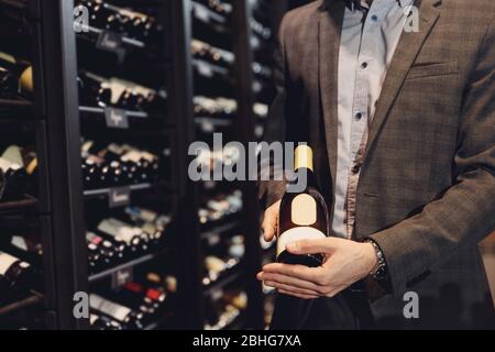 Il sommelier del barista preleva una bottiglia di vino dal rack nel ristorante con bevande squisite Foto Stock