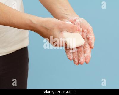 Donna lavando le mani con sapone su sfondo blu. La pulizia corretta delle mani protegge dalle infezioni. Concetto di igiene e pulizia. Foto Stock