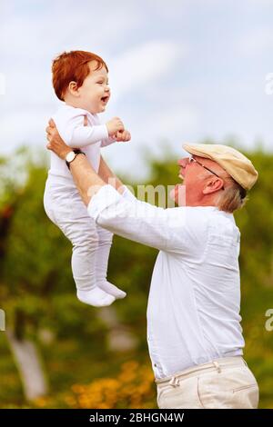 buon nonno giocare con il nipote bambino nel giardino primaverile Foto Stock