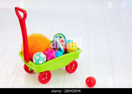 carrello giocattolo colorato pieno di palline tattili di diverso colore e forma per lo sviluppo dei bambini Foto Stock