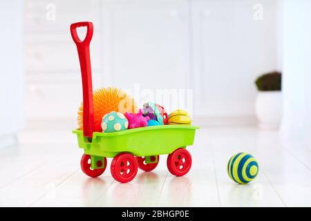 carrello giocattolo colorato pieno di palline tattili di diverso colore e forma per lo sviluppo dei bambini Foto Stock