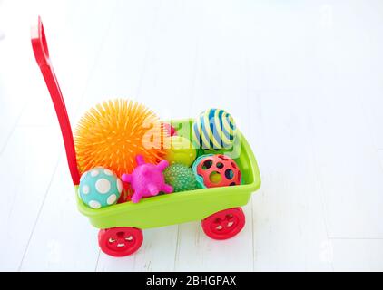 carrello giocattolo colorato pieno di palline tattili di diverso colore e forma per lo sviluppo dei bambini Foto Stock