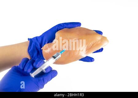 La gente fa siringa di iniezione in filetto di pollo su sfondo bianco Foto Stock